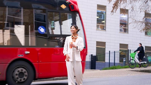 A young woman standing in front of a red double-decker bus